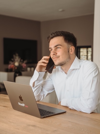 Noël Populiers aan het werk achter zijn laptop, klant aan de telefoon
